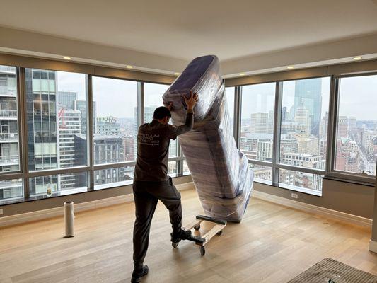 Perpetuum mover handling wrapped furniture with care, positioning it safely onto a four-wheeled dolly.