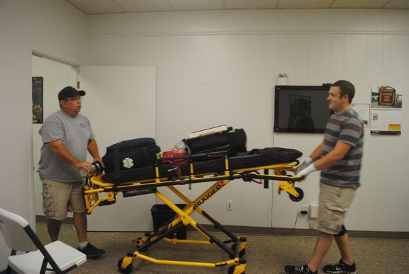Steven Hobbs, EMT Coordinator and Skills Instructor, works with a student on stretcher operations.