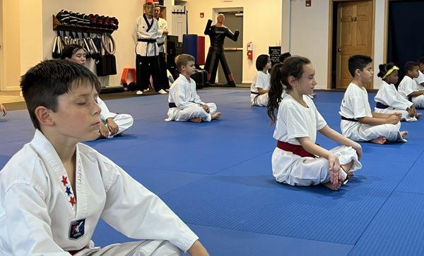 Middle and high belts doing some deep breathing and meditation after a challenging class. Teaching them to calm their minds and focus.