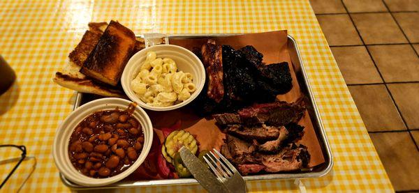 3 meat plate: brisket, ribs, burnt ends, beans, Mac n cheese, cornbread, and grilled bread.