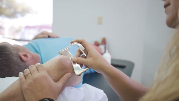 Dr. Jennifer Hauskey using a scraping tool to promote blood flow and reduce inflammation.