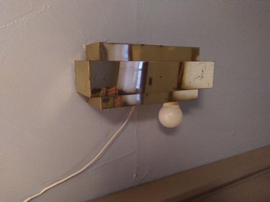 Light fixture above bed with bulb hanging out.