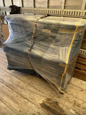 Pianos get blanket, wrapped and shrink wrapped and secured inside the moving trucks