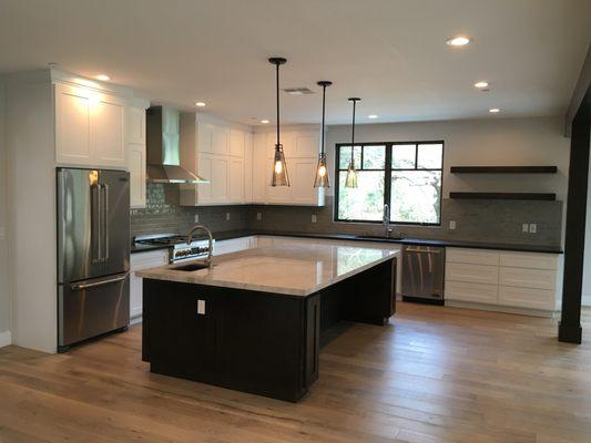 White painted kitchen cabinets, black stained island, black stained floating shelves.