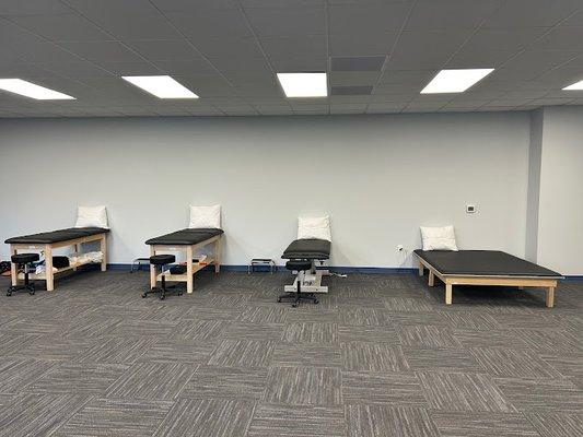 Spacious and clean physical therapy treatment room featuring multiple comfortable therapy tables.