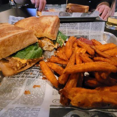 Hand breaded chicken sandwich with bang bang sauce and sweet potato fries.