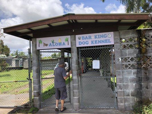 Man walking through front entrance with signs saying, "Aloha" and "Bar-King Dog Kennel."