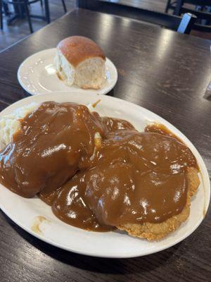Country Fried Steak w/mashed potatoes and gravy, and a large dinner roll.