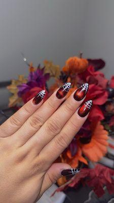 Red glass nails done with cat eye effect and hand designed spiderwebs!