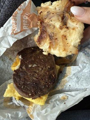 A biscuit with an old dried up patty and onions