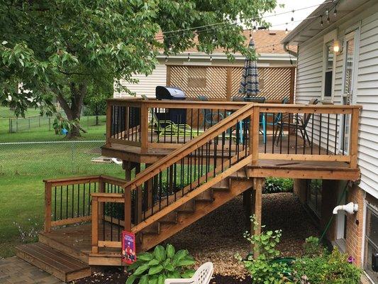 This new deck and stairs have a rail with aluminum Balusters / Privacy wall solid bottom top 1x2 cedar on a 45% angle. (630) 654-8400