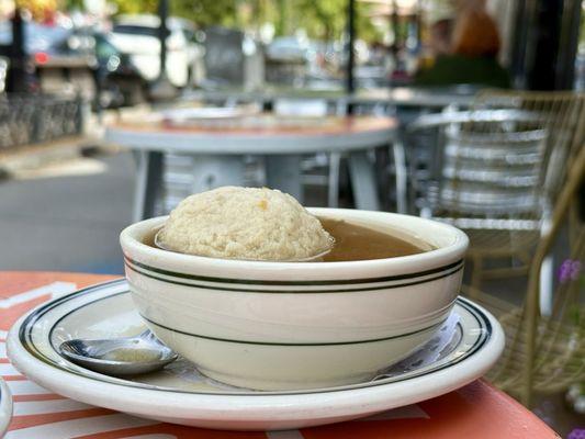 A hot cup of matzah ball soup enjoyed on the sidewalk patio.