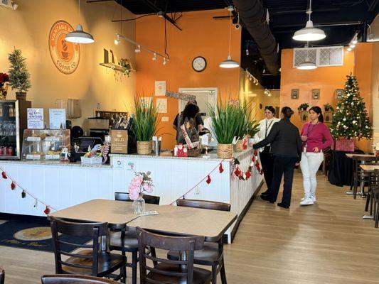 Most of the seating is wooden tables and chairs. However, there is bar-style seating at the front entrance area.