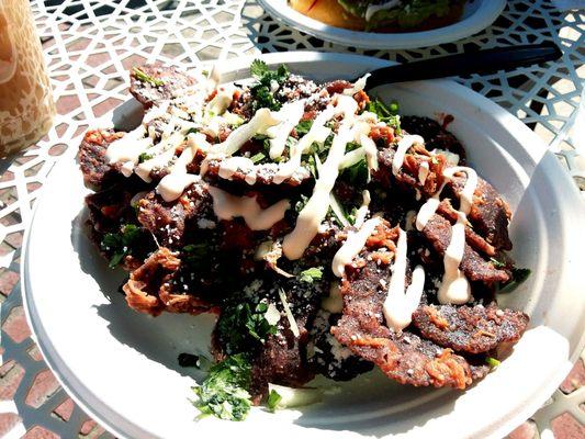 Chilaquiles with Pork loin- blue corn chips, cotija cheese, oaxaca crema, cilantro, and salsa roja