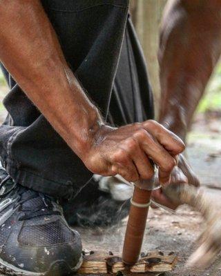 Teaching a student how to make fire from a bow drill.