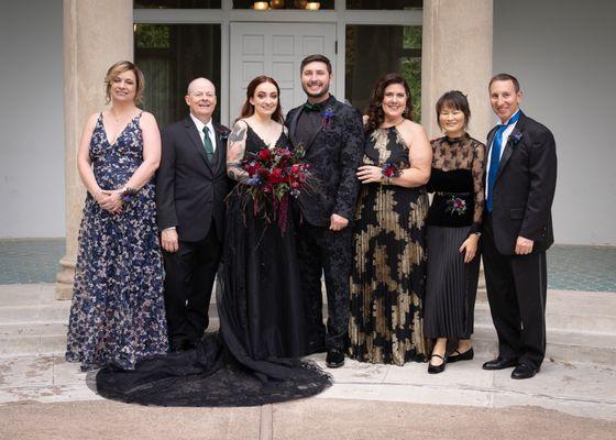 Hair and makeup done for woman on left, bride in center, and woman in black and gold dress