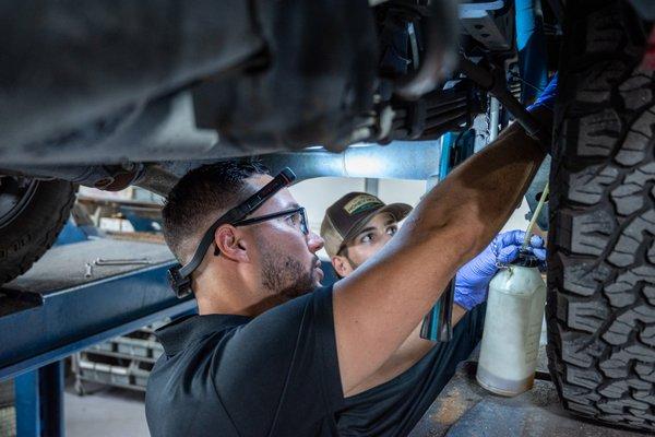 Daniel and Sergio are inspecting a client's vehicle, ensuring the customer is advised on the complete condition of their car.