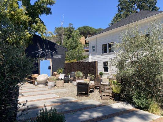 Several small shops and art studios sit between the interiors shop and the white building.