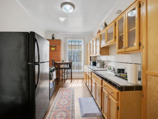 A kitchen with wooden cabinets and a black fridge