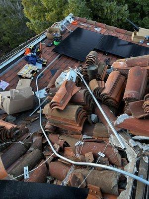 Roofing and conduit work being done to connect solar arrays.