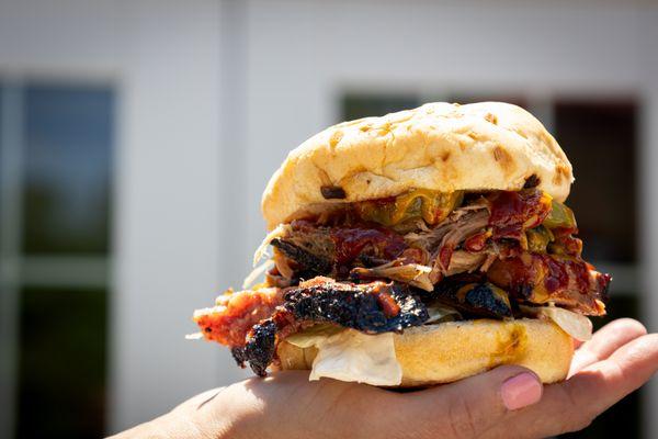 The Pit House Stack: towering flavor in every bite. Pulled pork, brisket, coleslaw, pickles, and bbq sauce.
