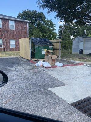 Trash is just left short of the dumpster because people are too lazy to lift their own crap!