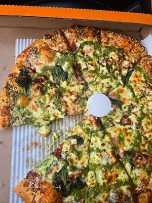 Spinach, feta, and tomato pizza with pesto drizzle and everything crust.