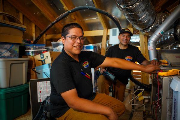 Honeycomb Heating and Cooling technicians in an attic space performing a tuneup.