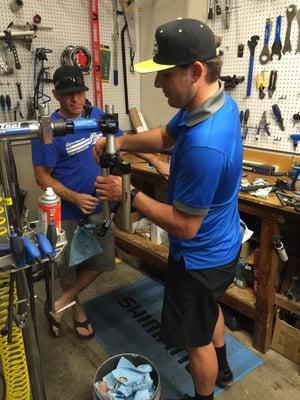 The store manager teaching a customer how to rebuild a front fork shock they thought they had to replace.