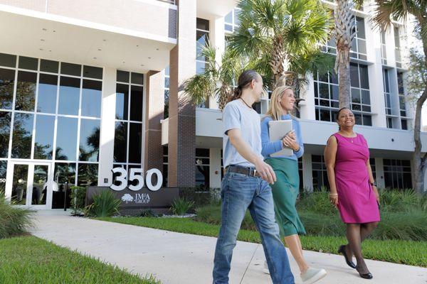 Associates walk in front of the JM&A Group logo.
