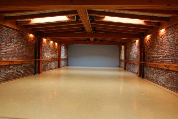 View of the inside of the studio. Skylights, brick walls, sprung marley floor.