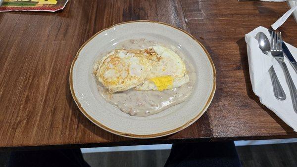 1/2 order of biscuits and gravy with two eggs on top.