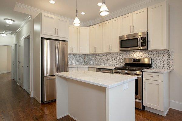 Kitchen with Stainless Steel appliances including 5 burner stove, mosaic tile backsplash & gorgeous carrera marble quartz counters & island