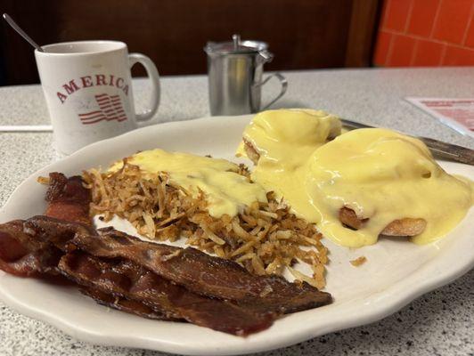 Eggs Benedict with hollandaise on the hash browns and bacon on the side