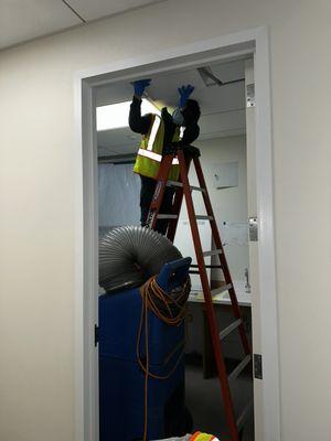 Our technician placing a ceiling panel back in place after cleaning an air duct at Stanford Children's Health Center.