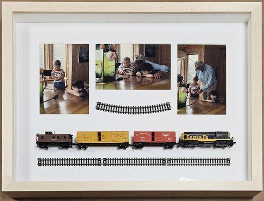 This is a shadowbox frame custom made to fit a toy train with photos of the grandfather with the kids playing with that train!