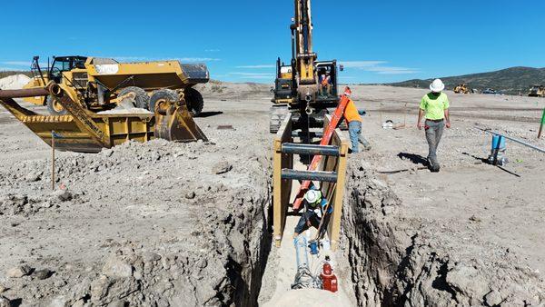 Excavator lowering waterline into trench at Deer Ridge project in Park City, Utah