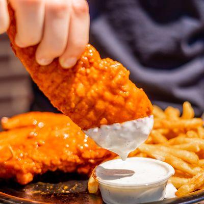 A chicken tender tossed in garlic hot buffalo sauce dipped in ranch