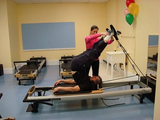 Nadya Beaudoin assisting her student performing Short Spine Massage on the Reformer.