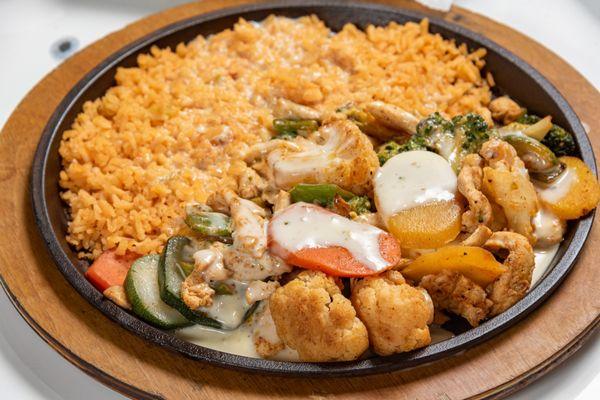 Skillet Supremo Grilled chicken, California Vegies Blend, with onions and bell peppers, served with a side of rice on a hot skillet.