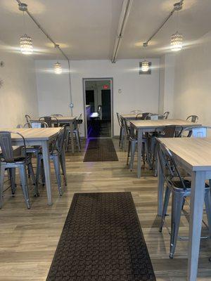 Dining area furnished with 6 squares tables and 24 chairs .