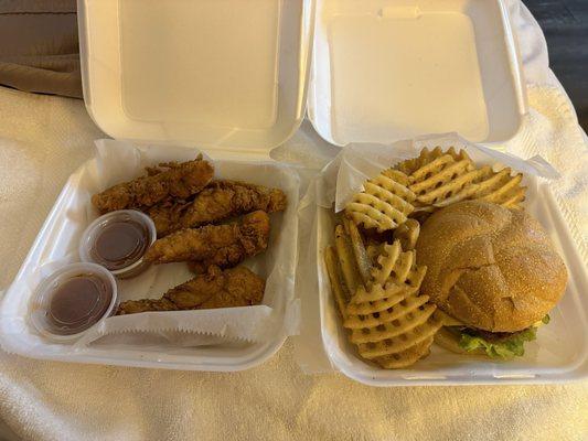 Chicken tenders and a cheeseburger with waffle fries.
