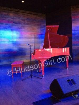 A red lacquered piano sits center stage