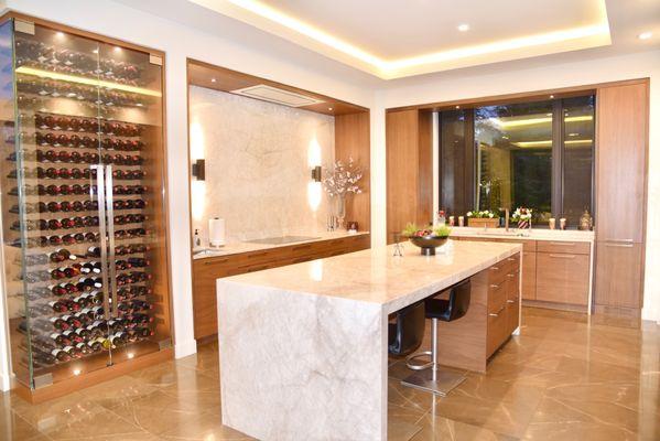 Luxury open kitchen with custom island, sleek cabinetry, and glass wine wall feature.