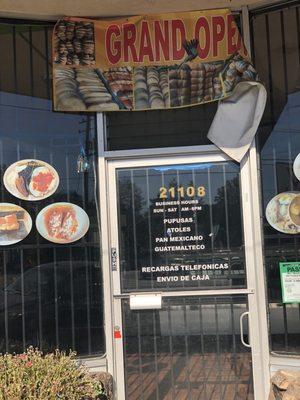 Grand opening sign with food pics on window