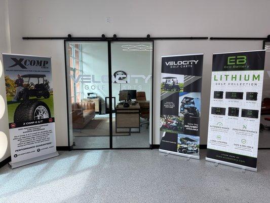 Front office of Velocity Golf Carts in Surprise, AZ, featuring partner displays from XComp Tires and Eco Battery alongside sh...