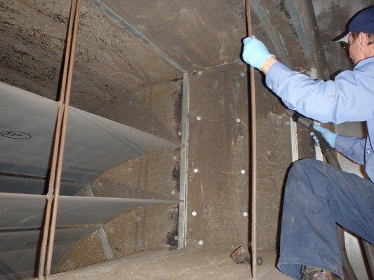 ACTS technician cleaning the interior of a commercial air handler,