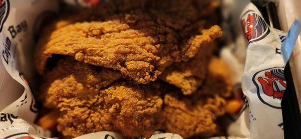 4 Fish fillets , fries and hushpuppies are underneath the fillets