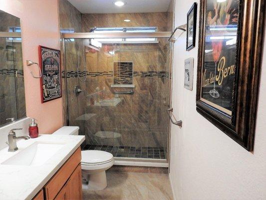 Bathroom remodel done with porcelain tile and decorative backsplash.