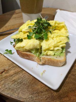 Avocado toast w/micro greens, add scrambled egg, minus chili flakes. ALOT of avocado hiding.  Bread lightly toasted to perfection.